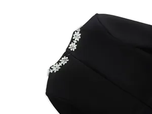 Close-up detail of luxury rhinestone floral embellishments on black neckline jumpsuit.