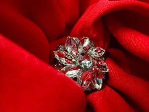 Detailed macro view of a sparkling crystal flower brooch nested in elegant red fabric folds