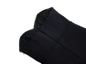Macro view showing pearl embellishments on the neckline of a black bandage evening dress