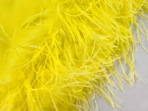 Makroansicht gelber Straußenfedern auf luxuriösem Stoff eines eleganten Abendkleids