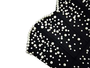 Close-up detail of luxury black bandage dress with elegant white pearl embellishments
