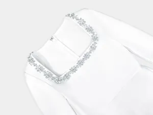 Close-up detail of white square-neck jumpsuit with sparkling floral rhinestone neckline