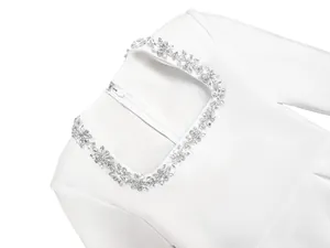 Detailed macro view of sparkling floral crystal rhinestones on a white square neck dress