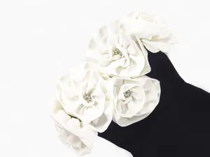 Detail view of white fabric roses with rhinestones on a black bandage dress.