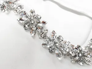 Close-up detail of sparkling floral rhinestone embellishments on a white bandage dress.