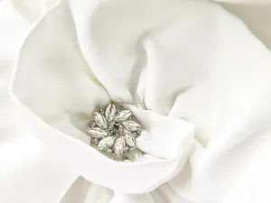 Detail of a luxury sparkling crystal flower brooch on white pleated bandage dress