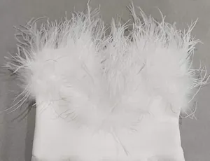 Detail view of fluffy white ostrich feather trim on a white bandage evening gown