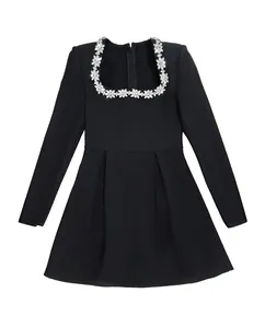 Detailed view of the sparkling rhinestone floral collar on an elegant black long sleeve dress