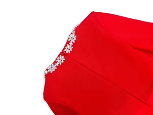 Macro detail of elegant flower rhinestone embellishments on a red jumpsuit neckline.