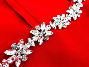 Close-up of sparkling rhinestone flower embellishments on red square neck jumpsuit.