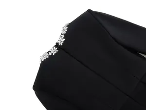 Close-up view of elegant rhinestone floral detail on a black French-style bandage dress.
