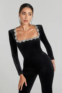 Close-up of elegant black velvet jumpsuit with rhinestone flower neckline detail.