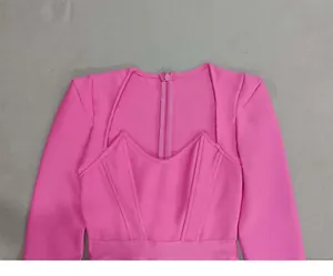 Detail view showing the padded shoulders and square neckline of a pink bandage dress