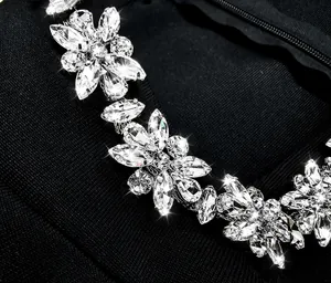 Close-up macro view showing exquisite rhinestone floral embroidery on black bandage dress fabric.