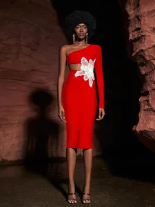 Close-up detail of red one-shoulder bandage dress with white lace flower and waist cutout