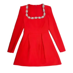 Detailed view of an elegant red long-sleeve dress with crystal flower embellishments