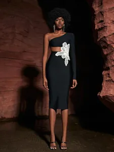 Detail view of black one-shoulder bandage dress with 3D white lace flower and waist cutout