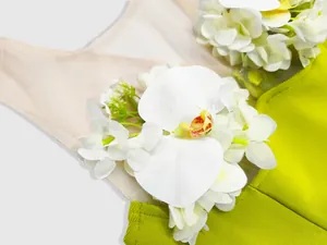 Close-up detail of elegant white 3D orchids and mesh on a lime green bandage dress