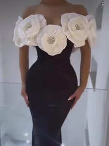 Detail of elegant black bandage dress with large white fabric flowers and crystals