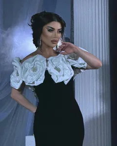 Detailed view of the elegant white floral appliques on a black bandage evening dress.