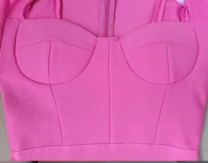 Close-up detail of hot pink bandage dress showing corset-style bust and ribbed texture.