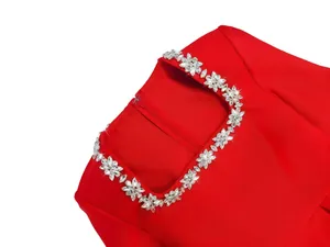 Close-up of elegant rhinestone flower neckline on a red French square neck dress