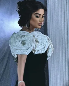 Close-up of white 3D fabric flowers with rhinestone centers on luxury black dress