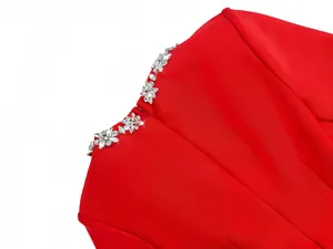 Detailed close-up of sparkling rhinestone embellishments on a red bandage dress