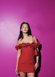 Detail showing the intricate 3D flower decorations on a red off-the-shoulder bandage dress