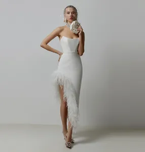 Detailweergave van een witte avondjurk met luxe struisvogelveren rand op een asymmetrische split.
