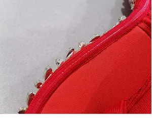 Macro view of sparkling crystal rhinestones on red bandage banquet dress detail.
