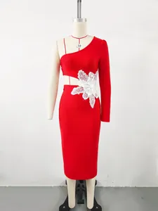 Close-up detail of a red one-shoulder bandage dress featuring a white lace flower