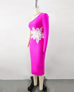 Detail view of a pink one-shoulder bandage dress with a large silver floral applique.