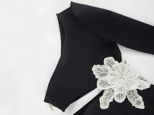 Close-up of black one-shoulder bandage dress with 3D white flower and side zipper detail.