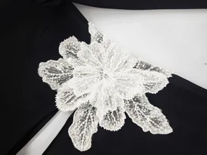 Macro view of exquisite white beaded lace flower applique on a black bandage dress