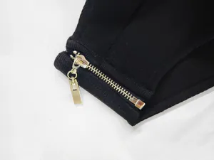 Close-up detail of the metal zipper and ribbed fabric texture on a black bandage dress