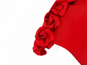 Detailed macro view of large 3D fabric roses on a red off-shoulder bandage dress
