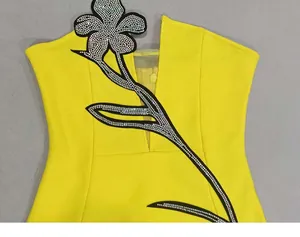 Detailed view of a yellow strapless dress featuring rhinestone flower and mesh