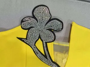 Macro view of the sparkling rhinestone flower applique on a vibrant yellow dress