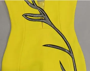 Close-up detail of yellow dress featuring intricate rhinestone floral pattern and mesh V-neckline