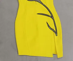 Close-up of yellow cocktail dress with elegant rhinestone floral pattern and side slit