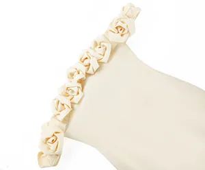 Close-up of 3D rose flower appliqués on the off-the-shoulder neckline of a cream bandage dress.