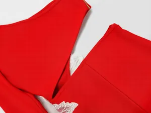 Close-up detail of a red one-shoulder bandage dress with white lace flower applique