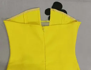 Detail view showing the back zipper and black floral accent on a yellow strapless dress.