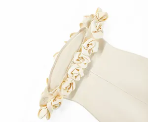 Close-up of off-the-shoulder cream bandage dress featuring intricate 3D floral detailing