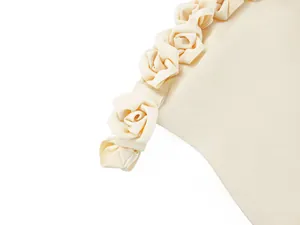 Detailed view of handmade fabric rose decorations on an elegant beige off-shoulder dress
