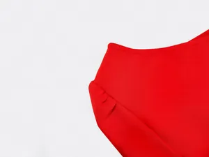 Close-up of pleated shoulder detail on a vibrant red bandage dress
