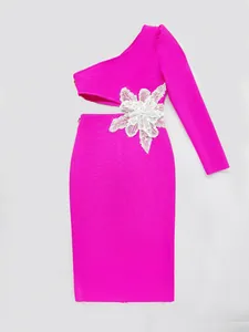 Detailed shot of a fuchsia one-shoulder bandage dress featuring a white floral waist accent