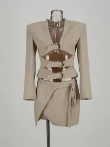 Beige two-piece set featuring a hollow long-sleeve buckle top and asymmetric mini skirt.