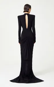 Elegant black long-sleeve evening gown featuring a dramatic open back and draped fishtail hem